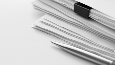 ballpoint pen resting next to a stack of papers